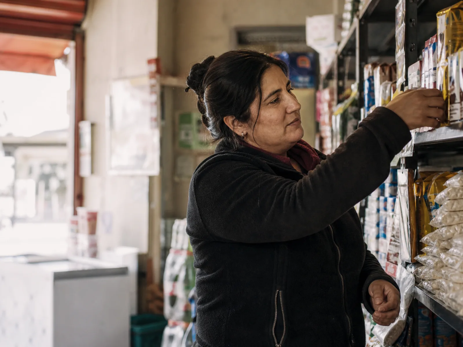 Dueña de un minimarket chileno revisando productos en una estantería